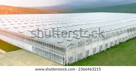 Aerial view industrial agricultural greenhouses for growing. Greenhouse industrial exterior. Food farming industry with giant buildings. Drone view on industrial modern glasshouse.