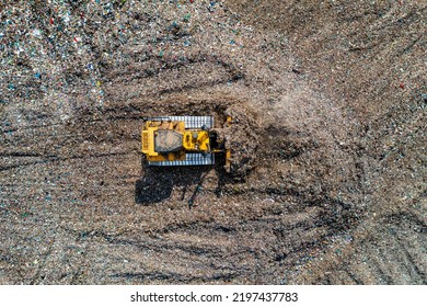 An aerial view of an industrial bulldozer moving household waste and gaebage on a large landfill site - Powered by Shutterstock