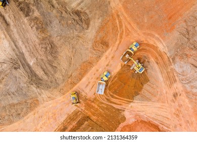 Aerial view of industrial crawler excavator in the process of work digs out earth and pours it onto the dumper truck at the construction site
