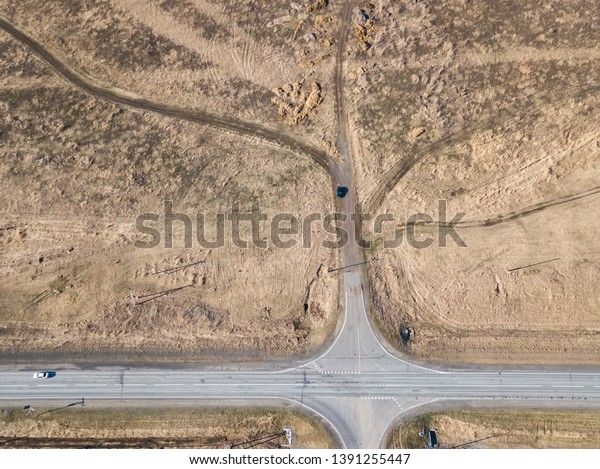 Aerial view of the intersection of asphalt and\
ground roads in the field far from the big cities on a clear spring\
day. Road junction in the\
desert.