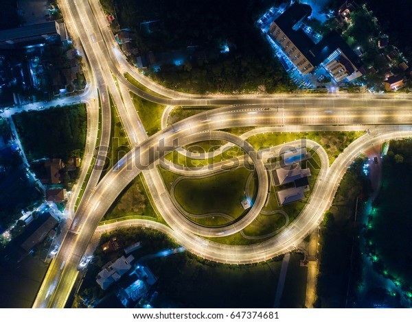 Aerial view at junctions of city highway. Road\
beautiful Aerial View of Busy Intersection at Night , top view ,\
thailand .Vehicles drive on\
roads.