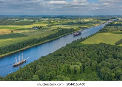 Aerial view of Kiel Canal with container ship and  traditional sailing vessel.Container cargo ship and tall ship on the Kiel Canal between Baltic sea and North Sea Schleswig Holstein, Germany.
