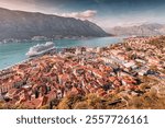 Aerial view of Kotor old town with orange rooftops and cruise ship in bay, at Montenegro, in beautiful autumn sunlight