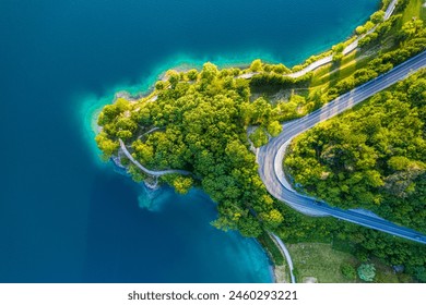  Aerial View of Lago di Ledro with Turquoise Water and Winding Road, Vibrant Summer Landscape in Northern Italy, Scenic Lakeside Route - Powered by Shutterstock