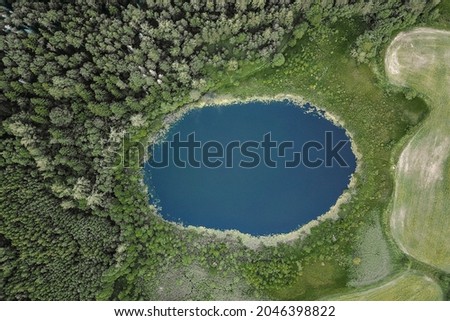 Aerial view of lake and forest  Small blue lake in green forest and fields