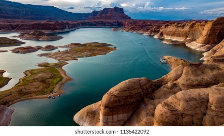 Aerial view of Lake Powell near Navajo Mountain, the San Juan River and Glen Canyon with beautiful black, pink, orange and red rocks and buttes. Clear, blue water and fluffy white clouds surround 