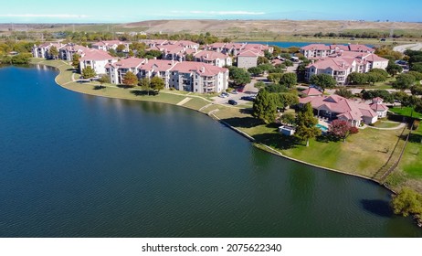 Aerial view lakeside apartment complex with landfill trash hill in background near Dallas, Texas, America. New development rental property multistory complex townhome with long sidewalk