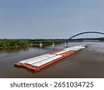 Aerial view of a large barge traveling under the Dale Gardner Veterans Memorial Bridge at Savanna illinois on the Mississippi River