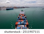 Aerial view of a large cargo ship entering a busy container port, showcasing maritime trade and logistics operations.