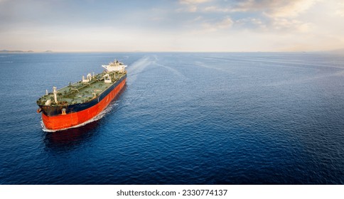 Aerial view of a large crude oil tanker traveling over calm sea during sunset with copy space