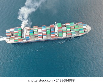 Aerial view of a large, loaded container cargo ship traveling over open ocea