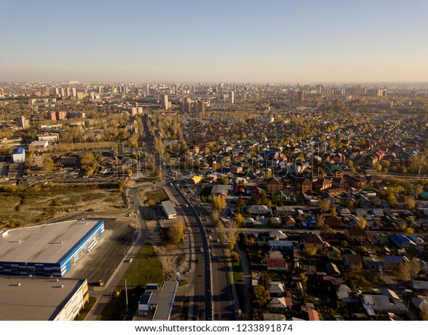 Aerial view of a large number of small houses on the\
outskirts of the city on an autumn afternoon during Indian summer\
with the road and cars