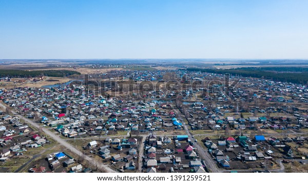 Aerial view of a large\
number of small houses with colored roofs on the outskirts of a\
small provincial town of Lenin Kuznetsk on an spring sunny day with\
the road and cars
