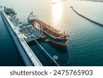 Aerial view of a large oil tanker docked at a pier in the port in process of loading.