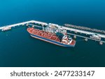 Aerial view of a large oil tanker docked at a pier in the port in process of loading.