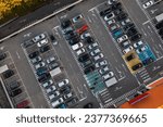 Aerial view of large parking lot in front shopping mall with many parked cars in European city. Carpark at supermarket with lines and markings for vehicle places and directions