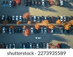 Aerial view of large parking lot with many parked colorful cars. Carpark at supercenter shopping mall with lines and markings for vehicle places and directions