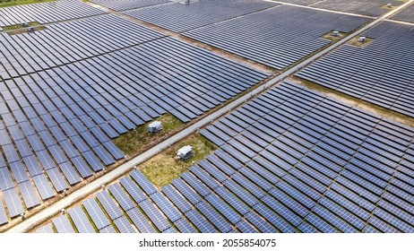 Aerial View Of A Large Scale Solar Panel Farm, Photovoltaic Panels. It Harvesting Sun's Power To Create A Flow Of Electricity. Reduce Reuse And Restore Concept