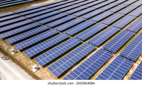 Aerial View Of A Large Scale Solar Panel Farm, Photovoltaic Panels. It Harvesting Sun's Power To Create A Flow Of Electricity. Reduce Reuse And Restore Concept