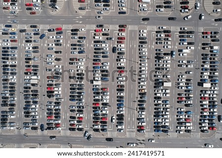 An aerial view of a large shopping center parking lot, filled with a multitude of cars.