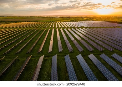 Aerial view of large sustainable electrical power plant with many rows of solar photovoltaic panels for producing clean electric energy at sunset. Renewable electricity with zero emission concept.