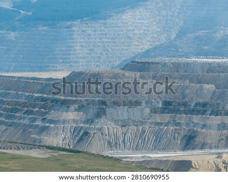 Aerial view of layered open-pit mine terraces and stripped earth revealing rock layers and industrial scars in British Columbia, Canada.