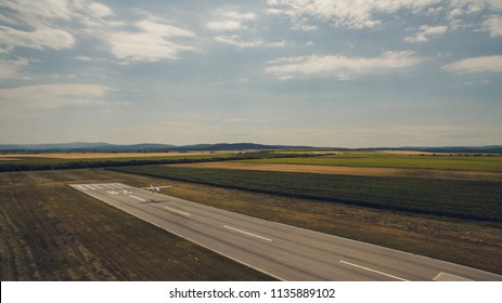 Aerial view of a light aircraft, landing at the runway of a small countryside airfiled