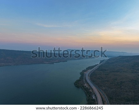 
aerial view light on super highway Along the Lam Takhong Dam at twilight.
view of natural scenery beside the road.
dams and wind turbines that generate electricity.
blue water and beautiful sky 