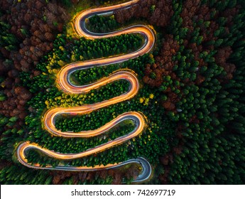 Aerial View Of Light Trails On A Winding Road Through The Forest At Night