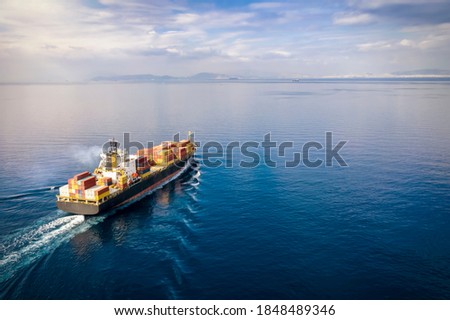Aerial view of a loaded cargo container ship traveling over calm ocean towards the next commercial port
