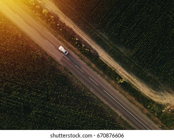 Aerial view of lonely car on the road driving towards sunset, drone point of view