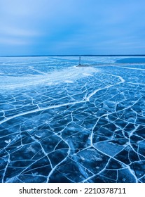 aerial view of a lonely lighthouse in the frozen sea. Frozen blue ice in cracks, drone view