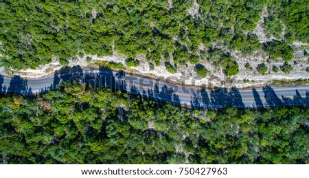 Aerial view looking down on curvy winding rural country road along mount Bonnell huge limestone cliffs in the Texas hill country traveling destination road trip