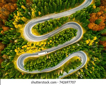 Aerial View Of Lorry Winding Up Its Way On A Curvy Road Through Autumn Colored Forest