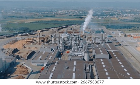 Aerial view of a lumber processing plant emitting smoke from its chimneys, showcasing industrial activity and environmental impact