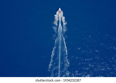 Aerial view luxury motor boat. Speedboat of white color with people moving on blue water in the rays of the sun. Speed boat movement at high speed aerial view.