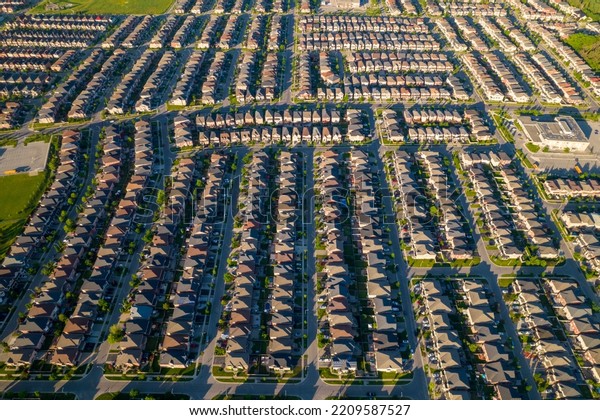 Aerial view of luxury wealthy style and clean
single family homes in America with parking space for cars and
large green backyards. Golden Hour evening and houses in very
geometrical setting
pattern.