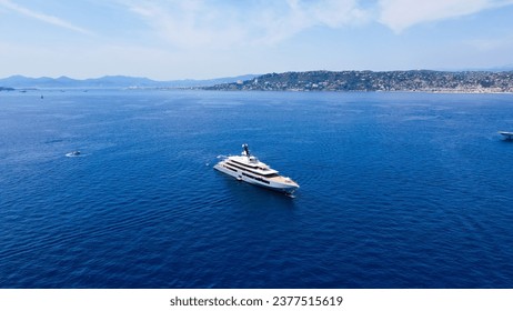 Aerial view of luxury yacht cruising in deep blue sea near Mediterranean. Drone tracking photo of modern yacht preparing to speed in Cap d'antibes, côte d'azur, Franch Riviera. Big white modern boat.