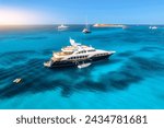 Aerial view of luxury yacht on blue sea at sunset in summer. Sardinia, Italy. Aerial view of speed boats, yachts, sea lagoon, coast, transparent water, sky. Top view from drone. Tropical seascape	