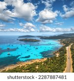 Aerial view of luxury yachts on blue sea at summer sunny day. Sardinia, Italy. Tropical seascape with speed boats, yachts, sea lagoon, island, transparent water, road, sky with clouds. Top drone view