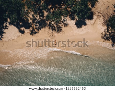 Aerial view of lying woman on the beach . Young woman on the sea. Phuket. Thailand. Top view. Seascape with girl on the seashore, blue water and waves. Travel