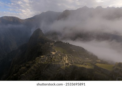 Aerial view of Machu Picchu in Peru with mist covering the ancient ruins and surrounding mountains. - Powered by Shutterstock