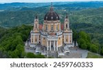 Aerial view of the majestic Basilica di Superga, nestled atop the lush hills of Torino (Turin), Italy, showcasing its grandeur against a dramatic sky.