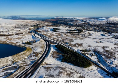 Aerial View Of A Major Road Running Through A Snowy Landscape (A465, Wales, UK)