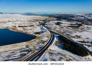 Aerial View Of A Major Road Running Through A Snowy Landscape (A465, Wales, UK)