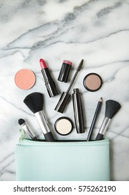 Aerial View Of Make Up Products Spilling Out Of A Pastel Blue Cosmetics Bag, On A White Marble Counter Top Background