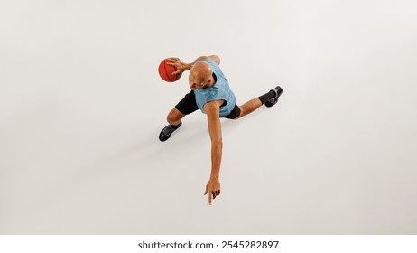 Aerial view of male basketball athlete dribbles basketball preparing for jump against grey studio background. Concept of sport event, competition, active and healthy lifestyle, game. - Powered by Shutterstock