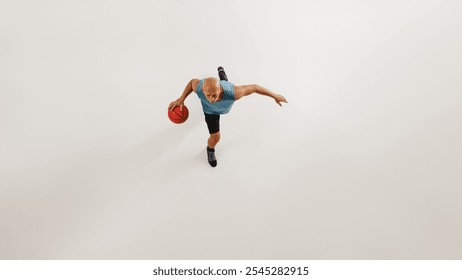 Aerial view of male basketball athlete dribbles basketball preparing for jump against grey studio background. Concept of sport event, competition, active and healthy lifestyle, game. - Powered by Shutterstock