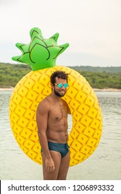 Aerial view of man with inflatable pineapple shaped mattress, smiling.