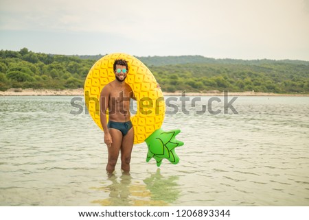 Aerial view of man with inflatable pineapple shaped mattress, smiling.